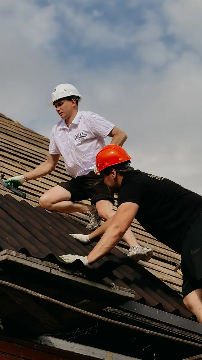 Couvreurs reposant des tuiles sur un pan de toiture en cours de rénovation
