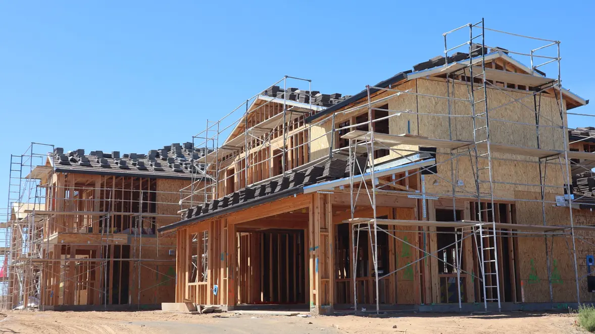Maison en chantier sous échafaudage, tuiles en attente sur la charpente