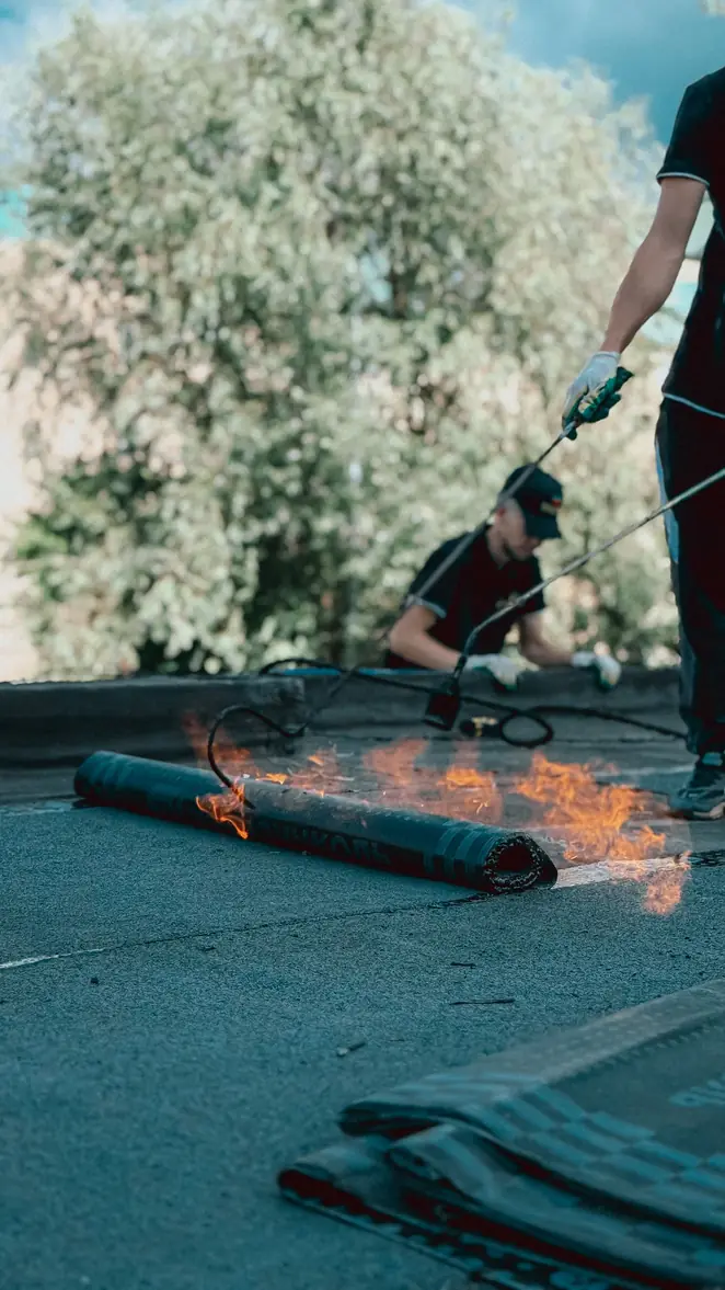 Soudure au chalumeau d'un rouleau bitumineux sur une toiture-terrasse
