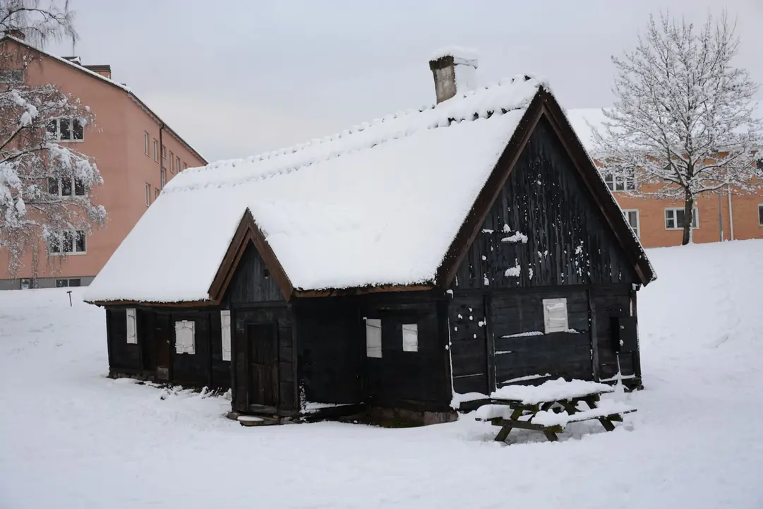Maison de bois sombre sous la neige dans un village de montagne