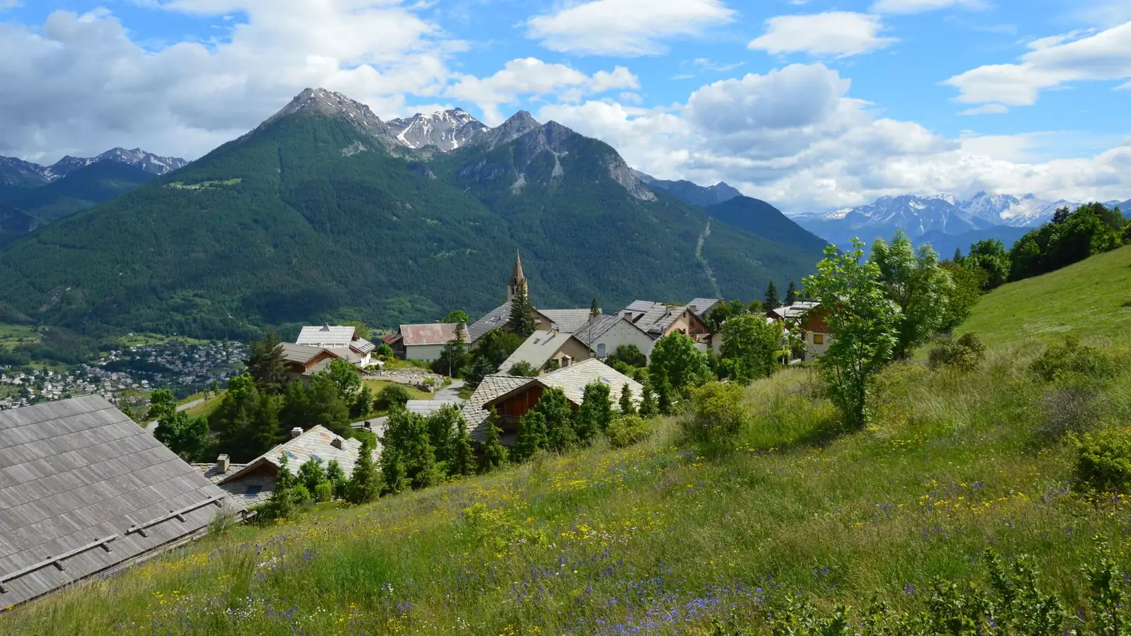 Panorama d'un village alpin et de sa vallée, massifs à l'horizon