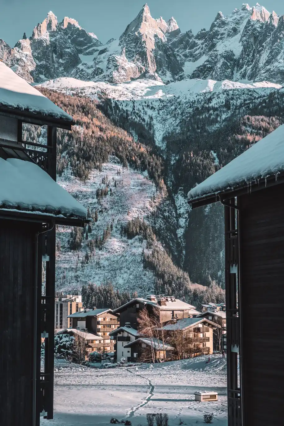 Village enneigé au pied d'un massif, toitures blanches sous la neige