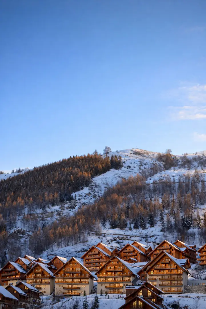 Toitures de chalets alignées sous la neige, vues depuis le versant