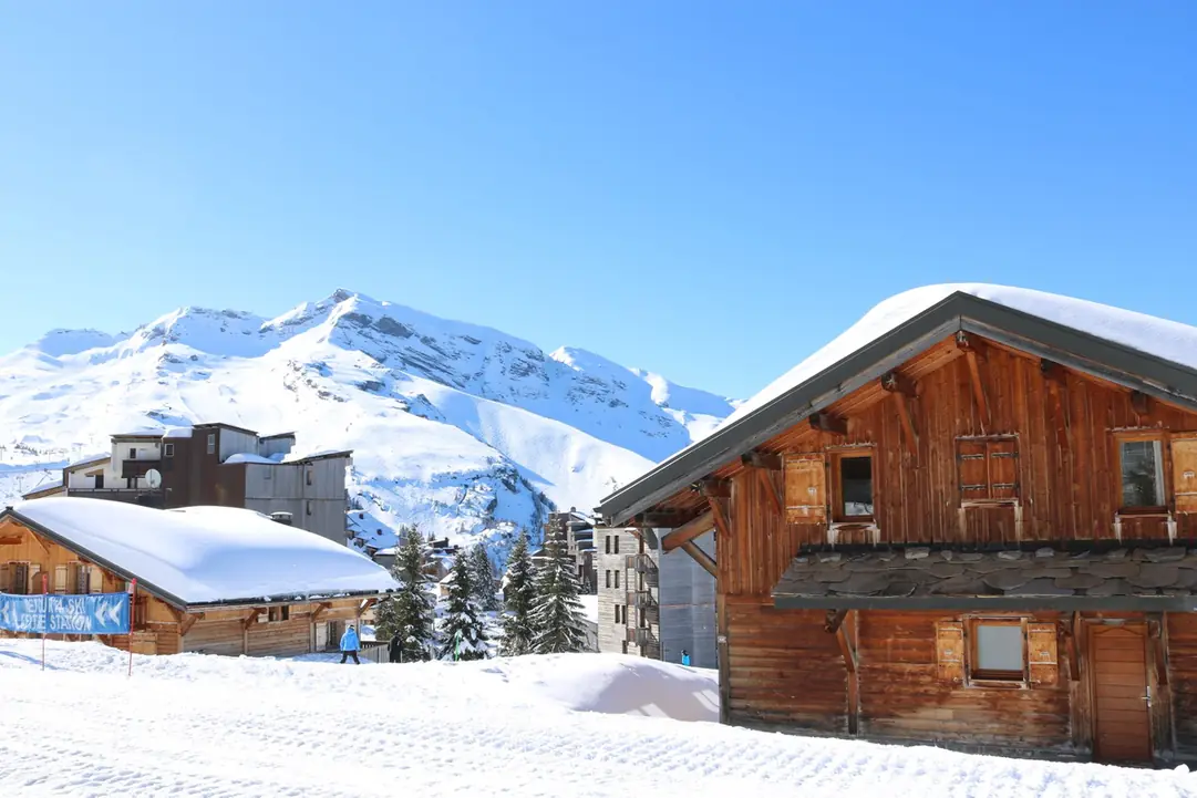 Chalet de bois en bordure de piste, pentes enneigées en arrière-plan