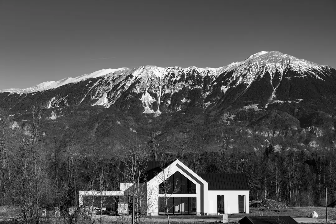 Maison contemporaine à toiture à deux pans devant un relief de montagne